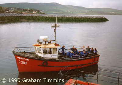 Many visitors will remember the Midnight Sun and her usual skipper Martin Flannery, seen here leaving the harbour with a gang of snorkellers kitted up ready to meet the dolphin. Small Martin took an especial interest in the dolphin and went out of his way to make sure swimmers had a good experience.
